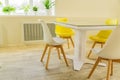 Modern dining room designed in scandi style. Glass table and yellow and white chairs Royalty Free Stock Photo