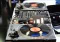 Modern DJ console with two vinyl players with records, mixers and connecting wires in the club