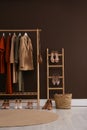 Modern dressing room interior with clothing rack near brown wall