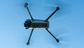 A modern drone against a clear blue sky. The quadcopter hovered motionless in the sky. The use of aircraft for reconnaissance and Royalty Free Stock Photo