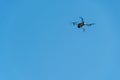 A modern drone against a clear blue sky. The quadcopter hovered motionless in the sky. The use of aircraft for reconnaissance and Royalty Free Stock Photo