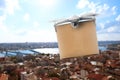 Modern drone with carton box flying above city on sunny day. Delivery service Royalty Free Stock Photo