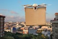 Modern drone with carton box flying above city on sunny day. Delivery service Royalty Free Stock Photo