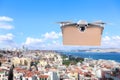 Modern drone with carton box flying above city on sunny day. Delivery service Royalty Free Stock Photo