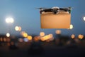 Modern drone with carton box flying above night city. Delivery service Royalty Free Stock Photo