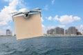 Modern drone with carton box flying above sea on sunny day. Delivery service Royalty Free Stock Photo