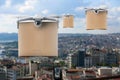 Modern drones with carton boxes flying above city on sunny day. Delivery service