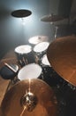 Modern drum set prepared for playing in a dark rehearsal room on stage with a bright spotlight. The concept of Royalty Free Stock Photo