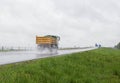 A modern dump truck for transporting bulk cargo drives on the highway in rainy weather. Safe driving in bad weather Royalty Free Stock Photo