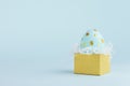 Modern easter egg with golden dots in golden gift box on blue background, copy space.