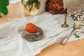 Modern Easter egg in nest on rustic table with spring flowers, candle,basket. Stylish red Easter egg painted in natural dye from Royalty Free Stock Photo