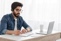 Modern education. Arab student guy learning online at home, looking at laptop computer, sitting at desk, free space Royalty Free Stock Photo