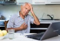 A modern elderly man is sitting at home, conducting an online consultation with a doctor on a computer Royalty Free Stock Photo