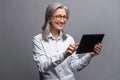 Modern elderly senior woman in formal wear using digital tablet isolated on gray Royalty Free Stock Photo