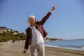 Healthy pensioner female walking outdoors along seashore