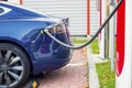 Modern electric car plugged to charging station in a parking lot Royalty Free Stock Photo