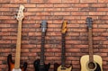 Modern electric and classical guitars near red brick wall