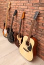 Modern electric and classical guitars near red brick wall indoors Royalty Free Stock Photo