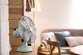 Modern electric fan on wooden table in living room. Space for text Royalty Free Stock Photo