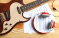 Modern electric guitar, headphones and music sheets on wooden background Royalty Free Stock Photo