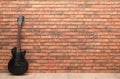 Modern electric guitar near red brick wall indoors. Space for text Royalty Free Stock Photo