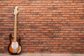 Modern electric guitar near red brick wall indoors. Space for text Royalty Free Stock Photo