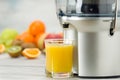 Modern electric juicer, various fruit and glass of freshly made juice, healthy lifestyle Royalty Free Stock Photo