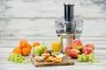 Modern electric juicer, various fruit and glass of freshly made juice, healthy lifestyle
