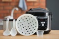 Modern electric multi cooker, parts and accessories on table Royalty Free Stock Photo