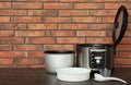 Modern electric multi cooker, parts and accessories on table near brick wall. Royalty Free Stock Photo