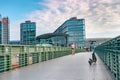 Modern electric scooter in front of modern steel and glass buildings and main train station Haupt Bohnhoff and running people in