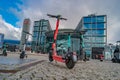 Modern electric scooter in front of modern steel and glass buildings and main train station Haupt Bohnhoff and traveling people