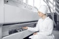 Modern electrical mill machinery for production of wheat flour. Woman operator checks quality of finished food products