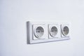 Modern electrical sockets on a white wall. Close-up of a triple rosette