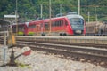 Modern electrical train with red engine on track on a suburban station. Passenger train rushing towards the city in a suburban