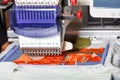 Computerized industrial embroidery machine with multicolored threads, close-up, selective focus