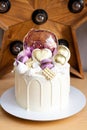 Modern elegant cake with melted white chocolate, golden heart and chocolate balls, macaroons, meringue and caramel.