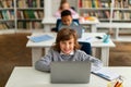 Modern elementary education. Happy school children sitting at desks with laptops, boy looking and smiling at camera Royalty Free Stock Photo