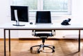 Modern empty office space desk with computer, phone and chair.