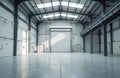 Modern empty warehouse interior with high ceiling and roller shutter door. Polished concrete floor reflects natural light from Royalty Free Stock Photo
