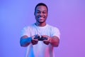 Modern Entertainment. Smiling Black Guy In Neon Light With Joystick In Hands
