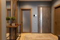 Modern entrance hallway in neutral shades of brown and gray tones in loft style. Video intercom on wall. Plant on console. Concept