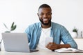 Modern Entrepreneur. Happy Black Man Sitting At Workplace With Smartphone And Laptop Royalty Free Stock Photo