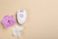Modern epilator and orchid flowers on beige background, top view. Space for text