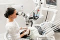 Modern equipment microscope in dental office. Young woman dentist treating root canals. Man patient lying on dentist Royalty Free Stock Photo