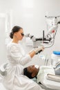 Modern equipment microscope in dental office. Young woman dentist treating root canals. Man patient lying on dentist Royalty Free Stock Photo