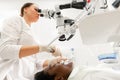 Modern equipment microscope in dental office. Young woman dentist treating root canals. Man patient lying on dentist Royalty Free Stock Photo