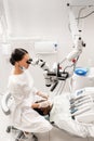 Modern equipment microscope in dental office. Young woman dentist treating root canals. Man patient lying on dentist Royalty Free Stock Photo