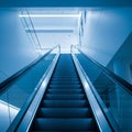 Modern Escalator Ascending in a Blue Lit Interior Space architecture blue lighting Royalty Free Stock Photo