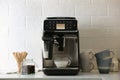 Modern espresso machine pouring coffee into glass cup with milk on white countertop in kitchen Royalty Free Stock Photo